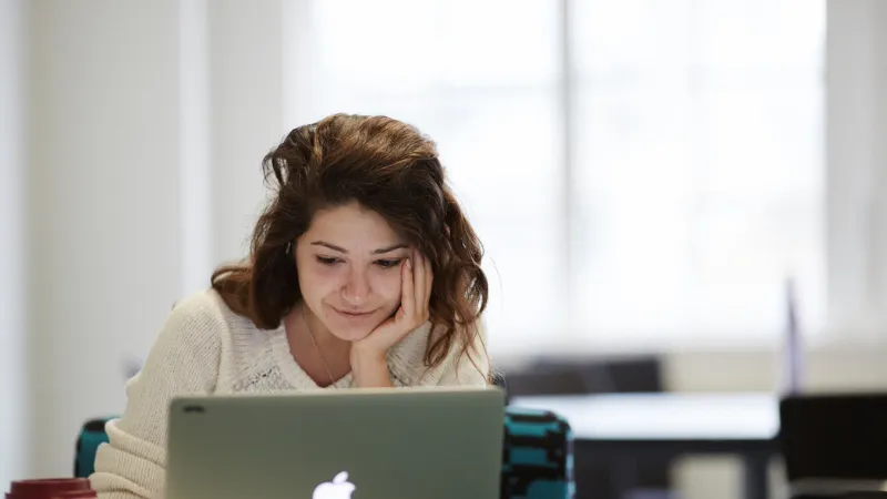 A person sitting on a sofa and looking at a laptop.